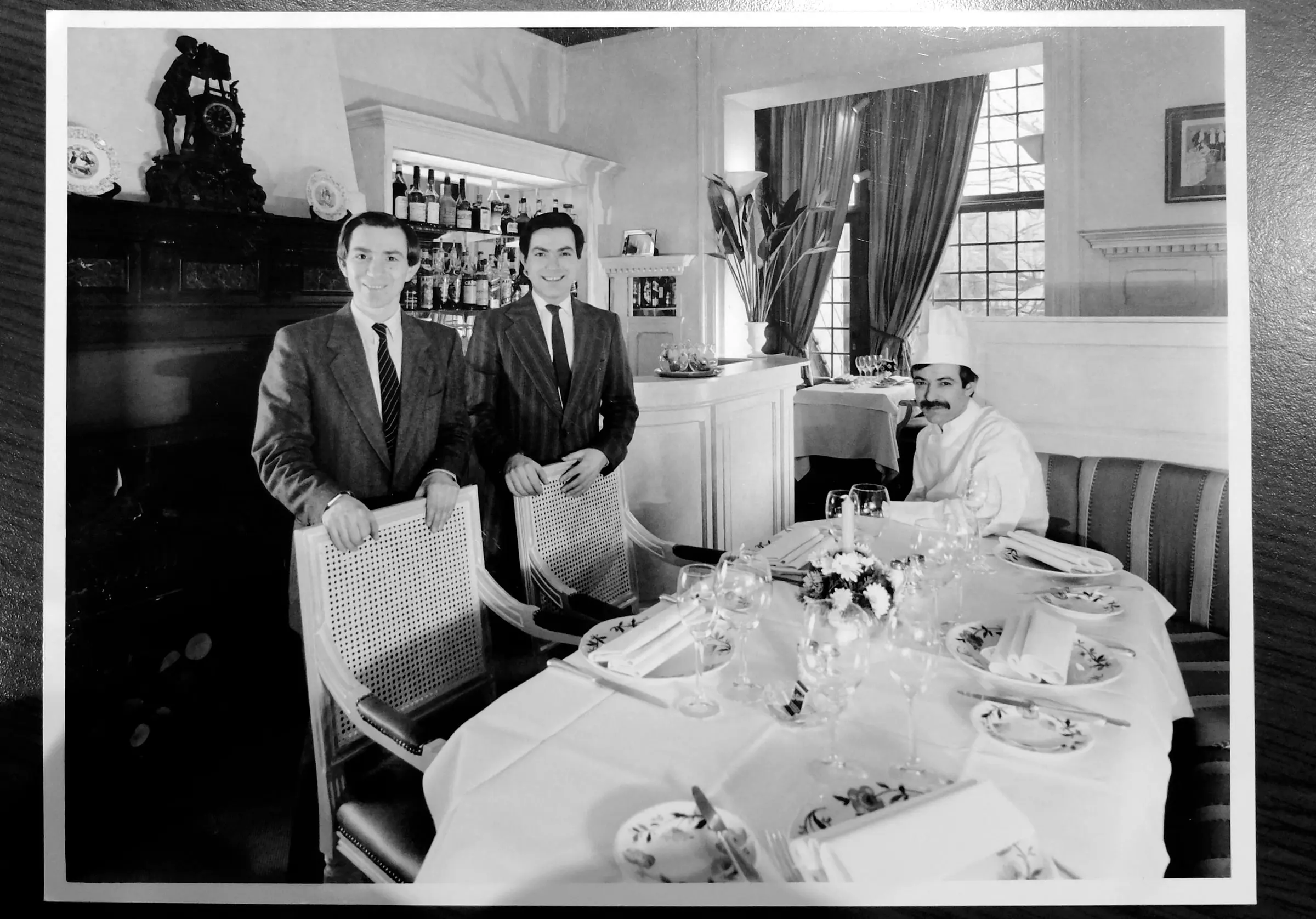 Photographie ancienne : deux hommes autour d’une table dressée dans la salle
