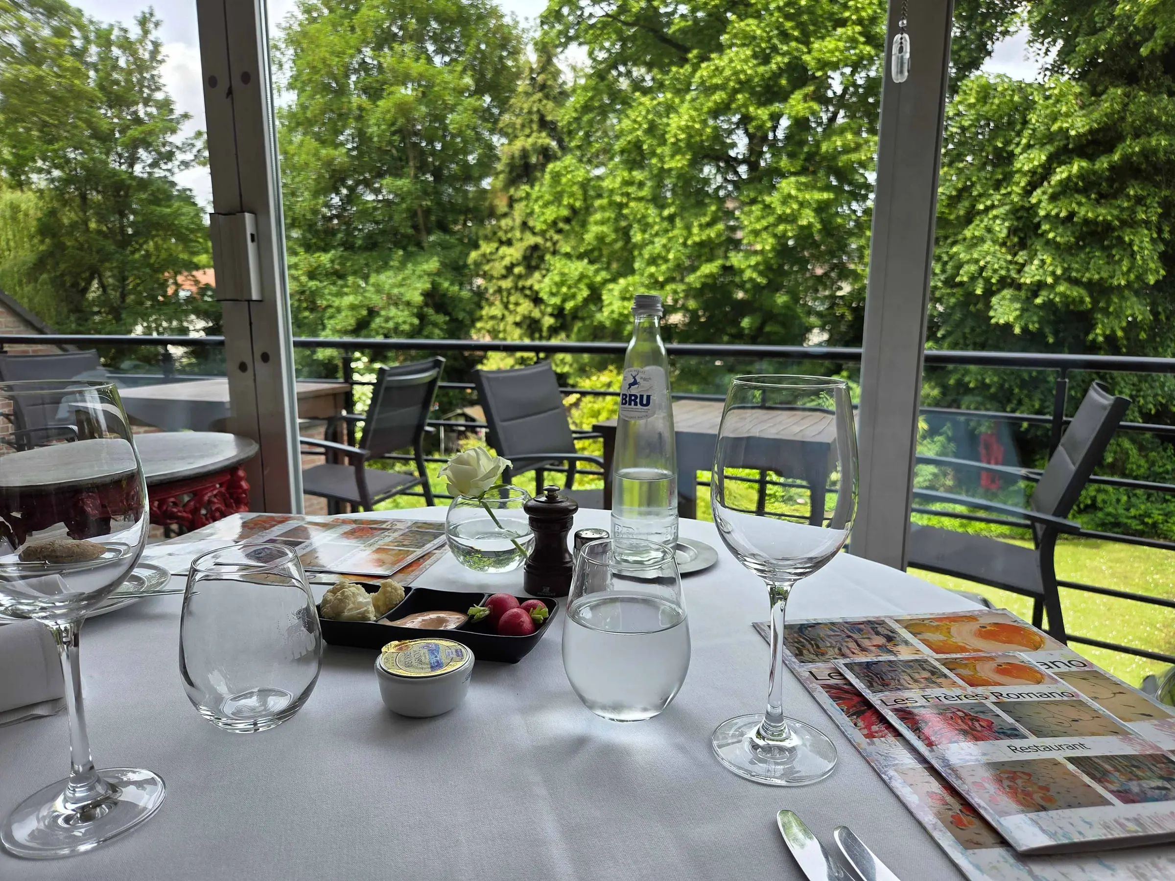 Table dressée sur la terrasse à la tombée du jour, face au jardin